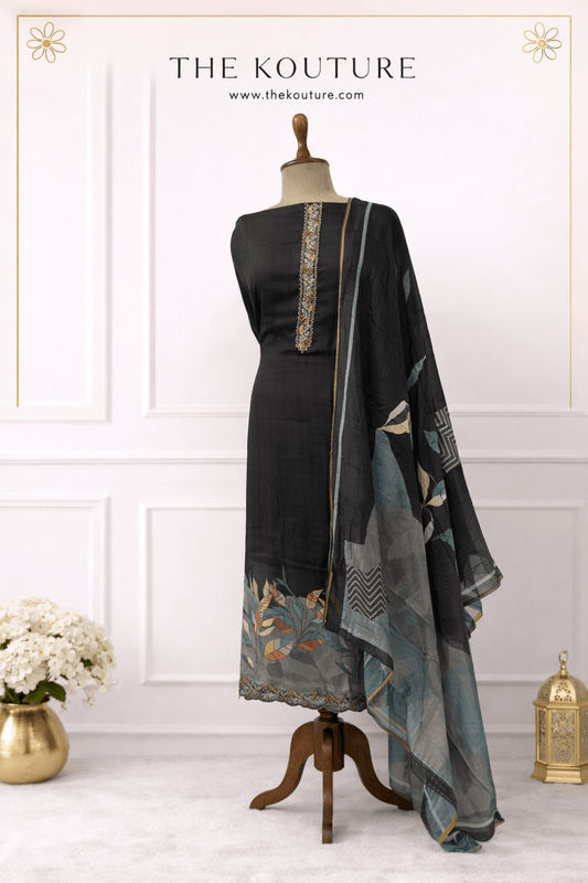 Black muslin suit set with printed dupatta for women displayed on a mannequin in an elegant setting.