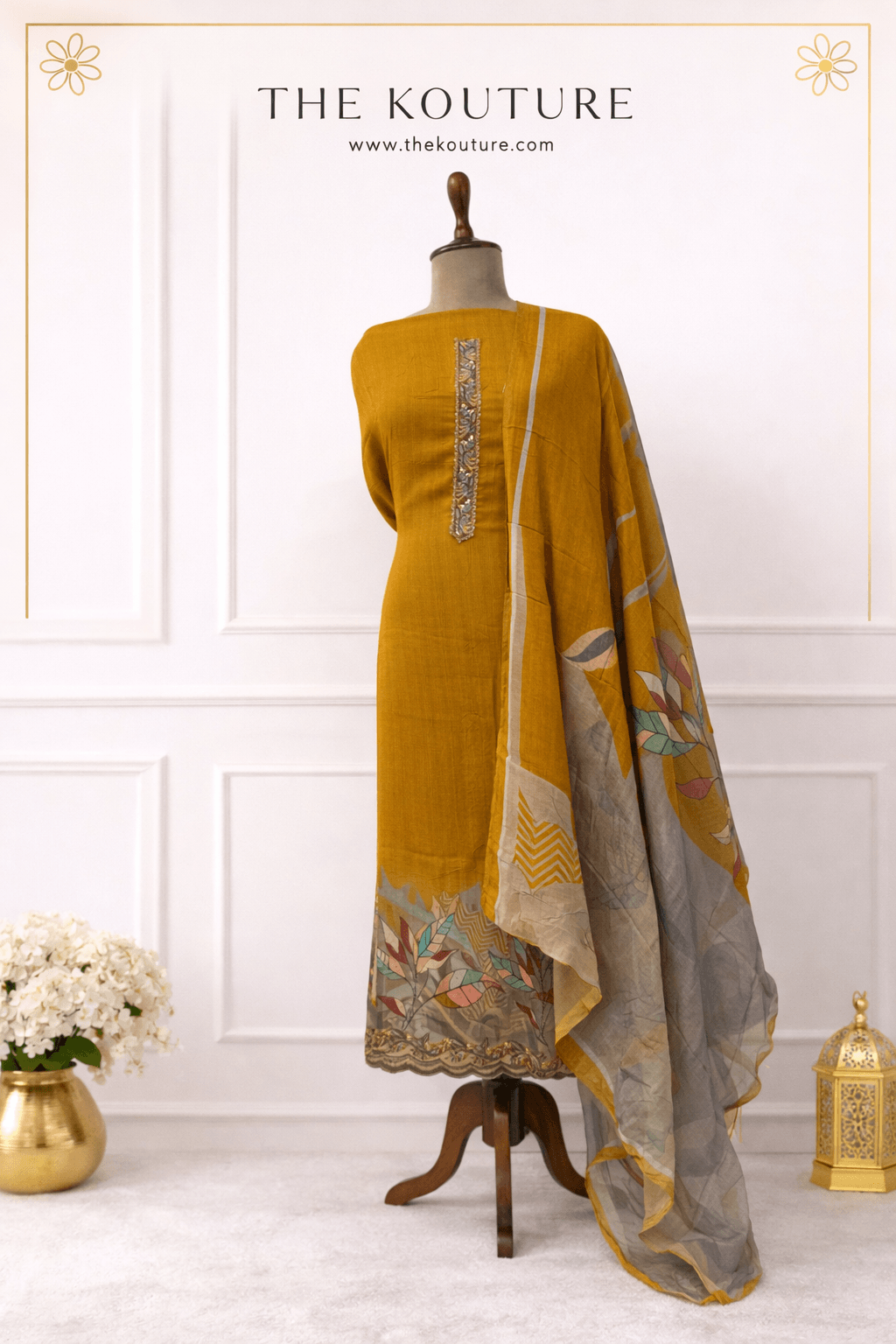 Mustard yellow suit set with printed dupatta displayed on mannequin, showcasing elegant design and premium fabric.